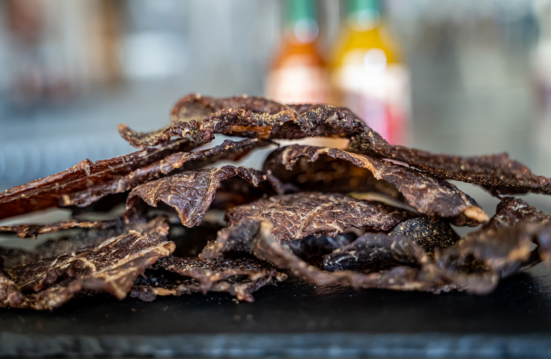 USDA-certified Tongue Stomper beef jerky with a signature dry texture, available in Original and Carolina Reaper flavors, offering bold taste and intense heat.